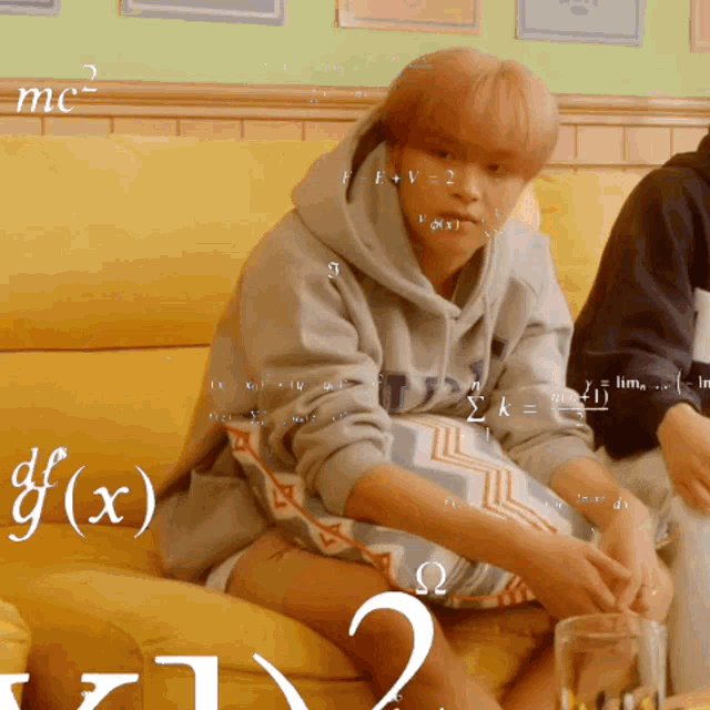a person is sitting on a yellow couch with mathematical equations on the wall