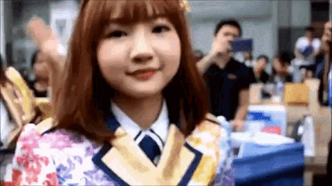 a girl in a floral dress and tie is standing in front of a crowd .