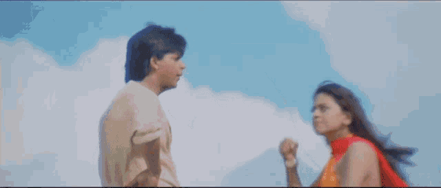 a man and a woman are standing next to each other against a blue sky .