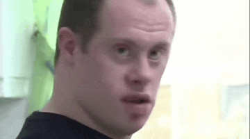a man with down syndrome is looking at the camera and making a funny face .