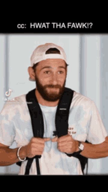 a man with a beard wearing a white hat and a backpack says " hwat tha fawk "