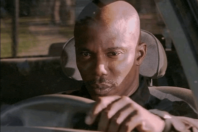 a bald man is driving a car and looking at something