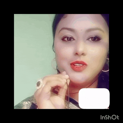 a woman with red lipstick and a ring on her finger looks at the camera with an inshot logo in the corner