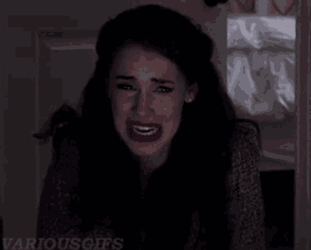 a woman is crying in a dark room with various gifs written on the bottom of the image