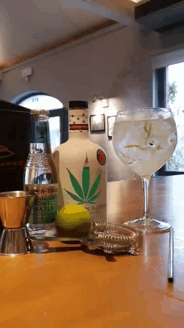 a bottle of tonic water sits on a table next to a glass