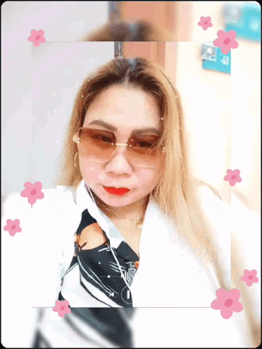 a woman wearing sunglasses is surrounded by pink flowers and the number 43 is on the wall behind her