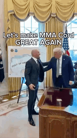 a man in a suit is standing next to a man in a suit and tie in a room .