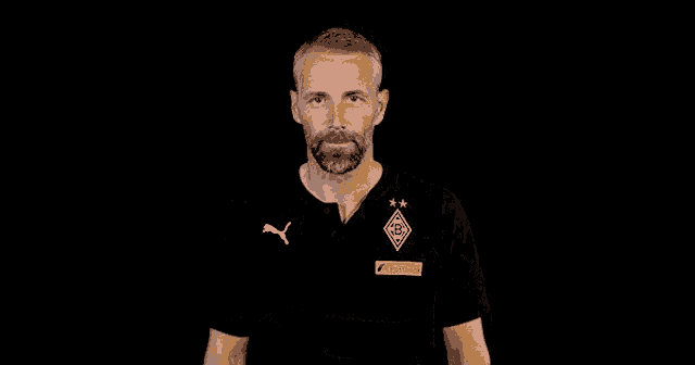 a man with his arms crossed wearing a black shirt with a puma logo on it