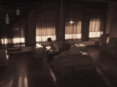 a man is laying on a bed in a dark room with a lot of windows