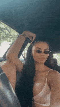 a woman wearing sunglasses is sitting in the back of a car