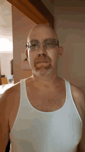 a man wearing glasses and a tank top looks at the camera