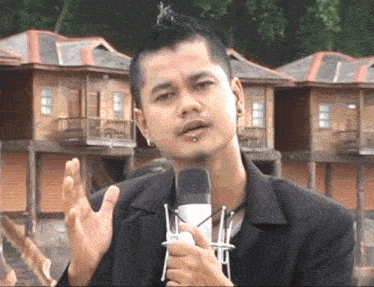 a man holding a microphone in front of a building