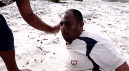 a man in a white shirt with the word arsenal on it is laying in the sand
