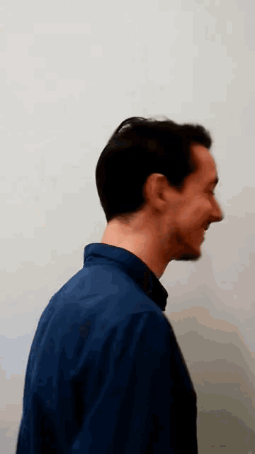 a man in a blue shirt is smiling and looking to the side