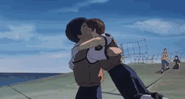a man and a woman are hugging each other in front of the ocean .