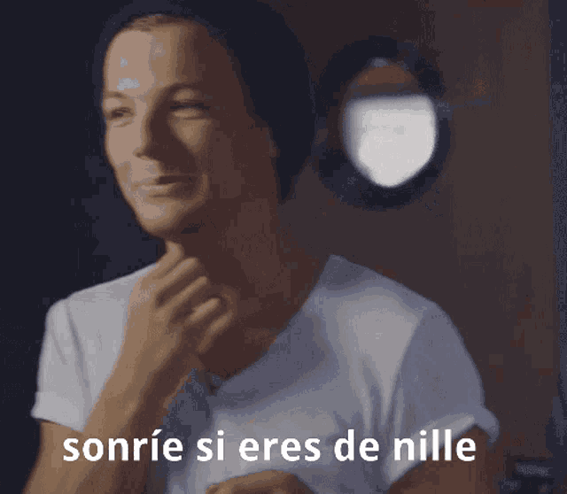 a man wearing a beanie and a white shirt with the words sonrie si eres de nille below him