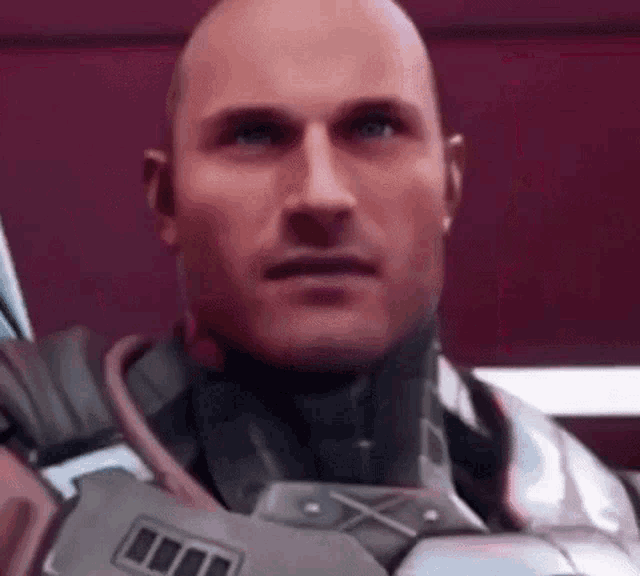 a bald man in a futuristic suit is looking at the camera