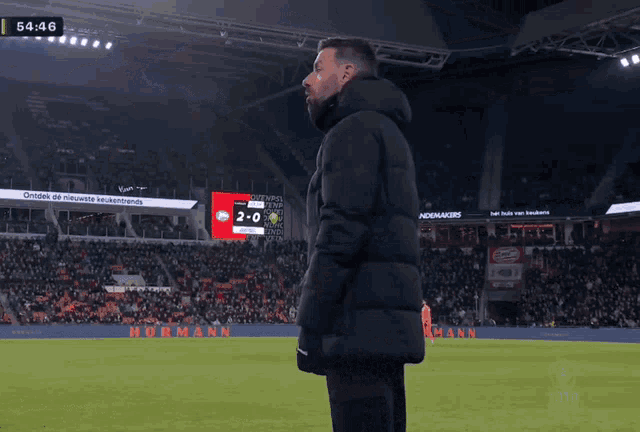a man stands on a soccer field with a scoreboard that says 2-0