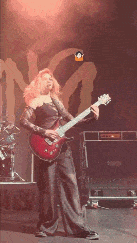 a woman playing a guitar on a stage with the letter n on the wall behind her