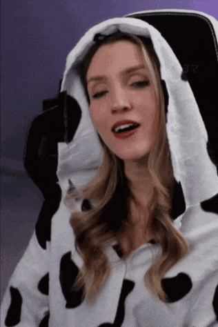 a woman in a cow print hoodie is sitting in a chair .
