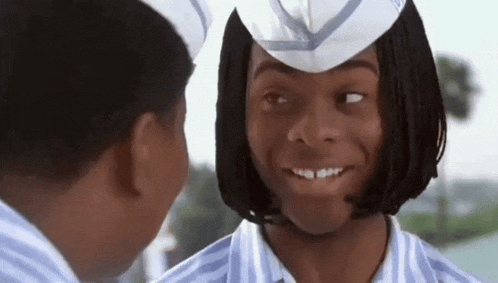 a man wearing a white hat is smiling while another man looks on