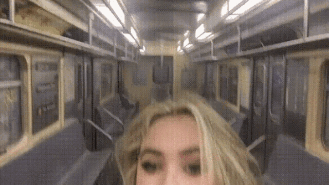 a woman takes a picture of herself on a subway car