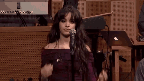 a woman in a purple dress is singing into a microphone in a room .