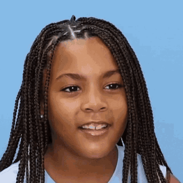 a young girl with braids on her head is smiling for the camera
