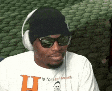 a man wearing headphones and sunglasses is wearing a shirt that says ' u is for halloween '
