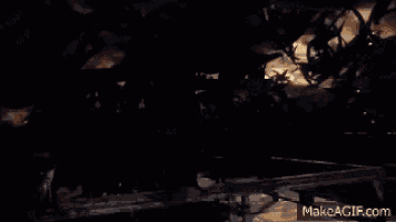 a man in a black robe is standing in front of a group of monsters in a dark room .