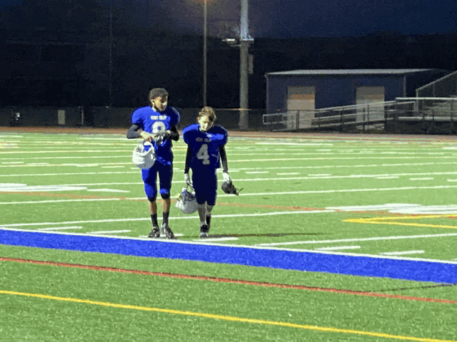 two football players walking on the field with one wearing number 4
