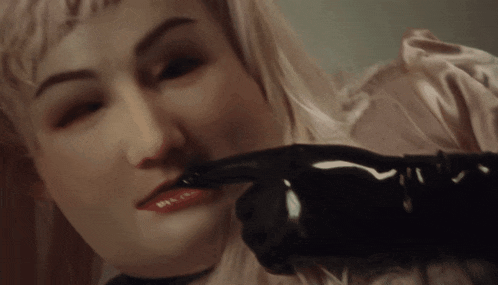 a close up of a woman 's face with a black glove on