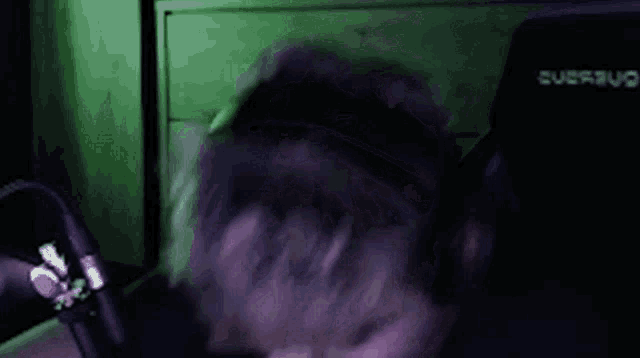 a man wearing headphones is sitting in front of a microphone and making a funny face .