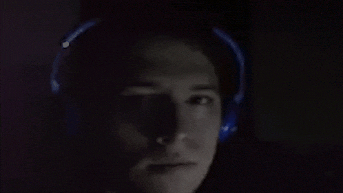 a man wearing blue headphones is looking at something in the dark