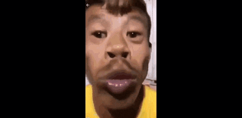 a man wearing a yellow shirt is making a funny face with his mouth open .