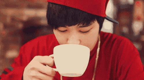 a young man is drinking a cup of coffee .