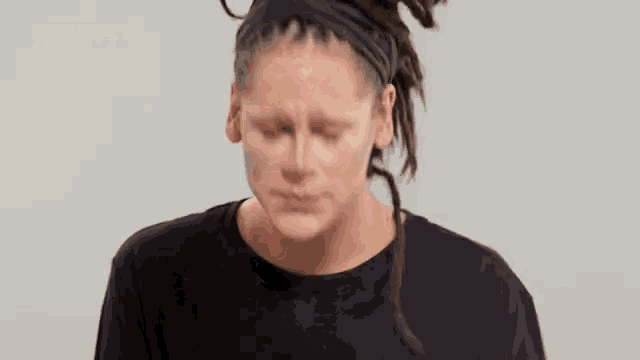a woman with dreadlocks is wearing a black shirt and a headband .