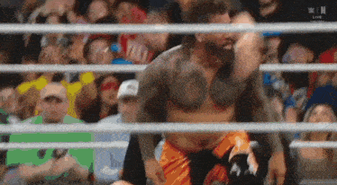 a man in a wrestling ring is being lifted by another man .