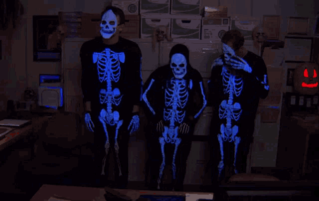 three people in glow in the dark skeleton costumes pose for a photo