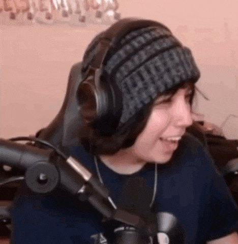 a person wearing a beanie and headphones is sitting in front of a microphone .