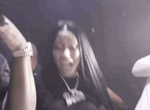 a woman with long black hair is dancing in a club with her hands in the air .