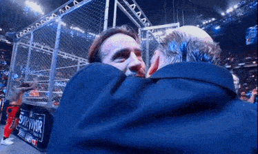 two men hugging in front of a sign that says survivor on it