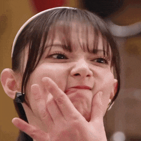 a close up of a girl making a funny face with her hand on her face .