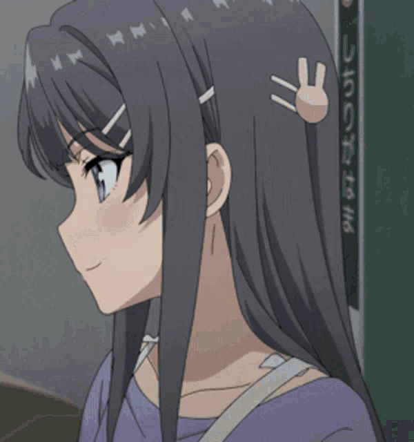 a girl in a purple shirt is holding a piece of paper to her face .