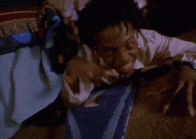 a man is laying on a bed making a funny face with his hands .