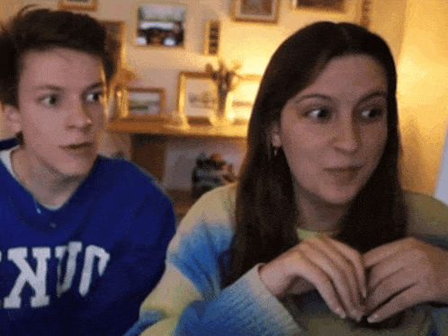 a boy and a girl are looking at each other and the girl is wearing a blue sweater that says nup