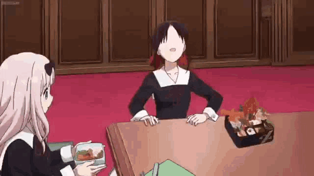 two anime girls are sitting at a table with a box of food on it .