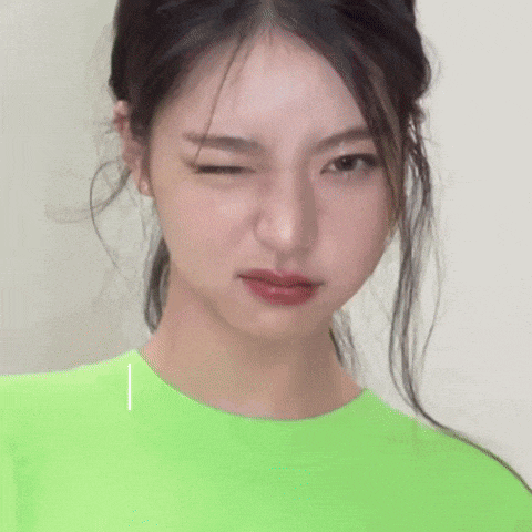 a woman in a green shirt is making a funny face .