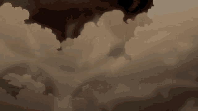 a person flying through a cloudy sky with a red wing