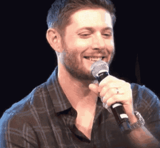 a man with a beard is holding a microphone in his hand and smiling .
